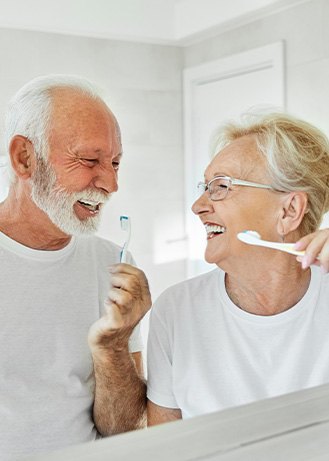 Senior couple smiling while brushing their teeth