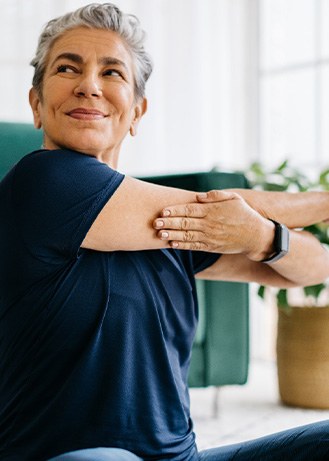 Senior woman smiling while stretching at home