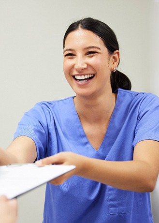 Woman smiling while handing patient form