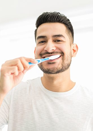 Man smiling while brushing teeth