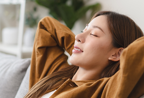 Woman relaxing on a couch with her hands behind her head