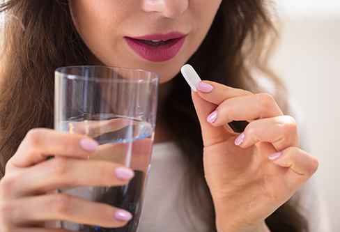 Woman taking a pill with a glass of water