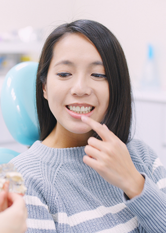Woman pointing to her teeth while talking to her dentist