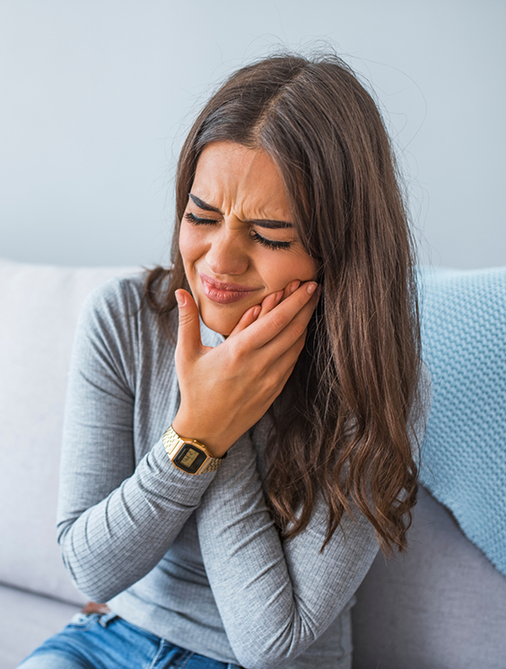 Woman holding the side of her jaw in pain before seeing an emergency dentist in Stratford