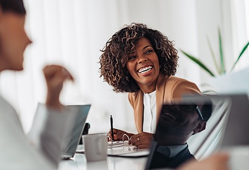Woman smiling while taking notes during meeting