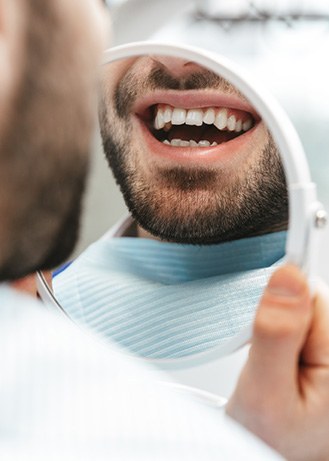Patient smiling at reflection in handheld mirror