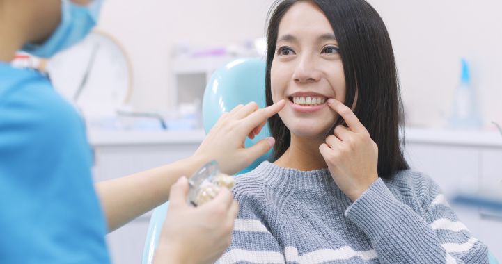 A woman pointing to her dental implant at the dentist