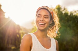 Woman smiling with sun rays in background.