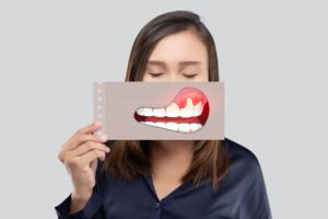 Woman with eyes closed holding image of swollen gums over mouth
